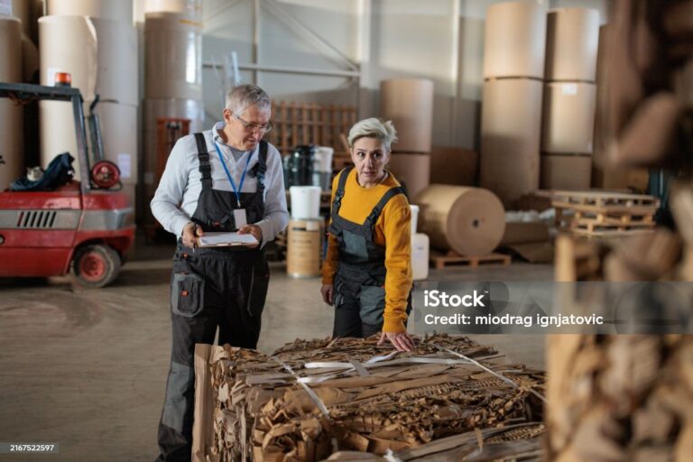 A mature Caucasian woman and senior Caucasian man inspecting merchandise in the storage warehouse of a paper factory